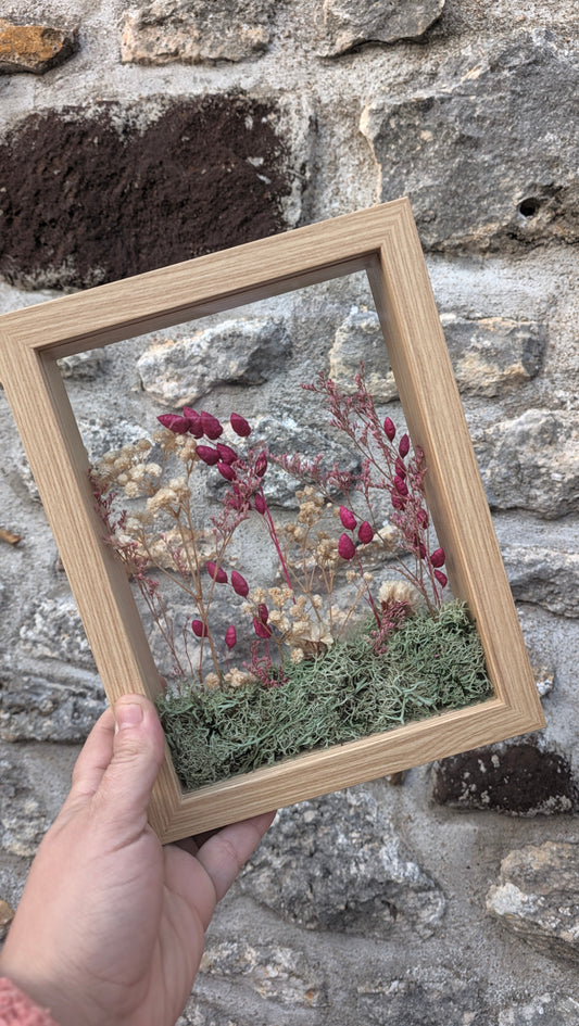 Cadre floral Le Jardin des brumes de la collection Soria tenu en main, création en volume avec véritables fleurs séchées et mousse.