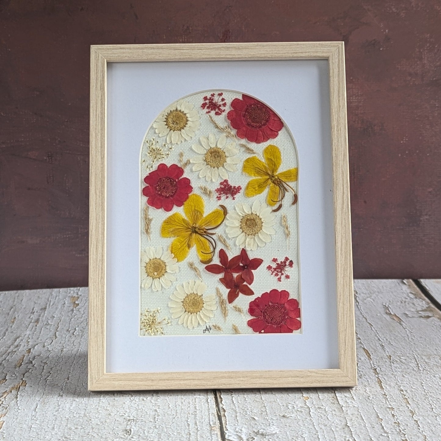 Cadre Florésie en forme d’arche avec composition de fleurs séchées pressées rouges, jaunes et blanches