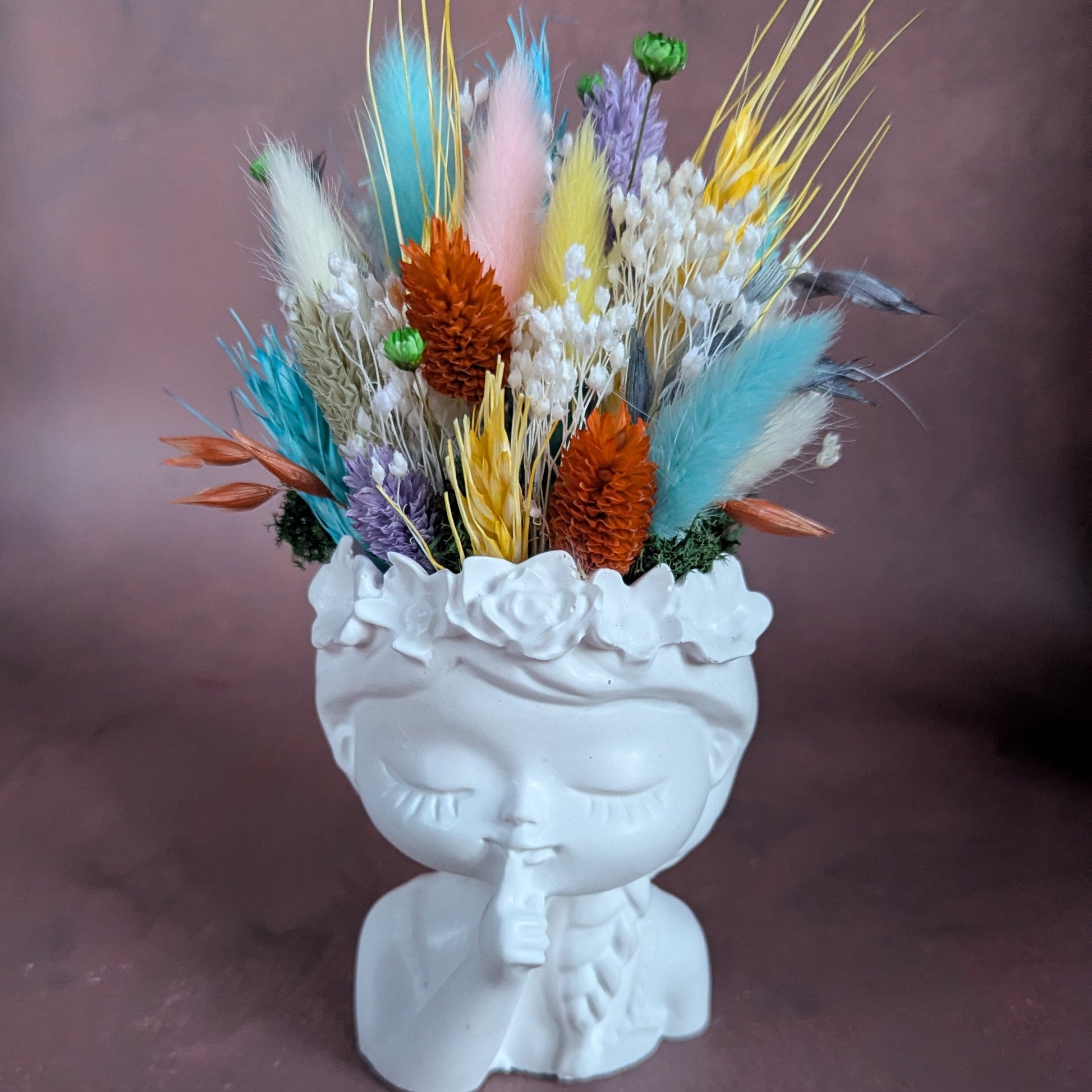 Gardienne en résine minérale de couleur blanche coiffé de fleurs séchées multicolore.