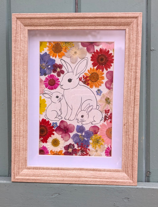 Cadre La famille de Max de la collection Faunéa, illustration d’une maman lapin et ses deux petits entourés de véritables fleurs séchées sous presse.