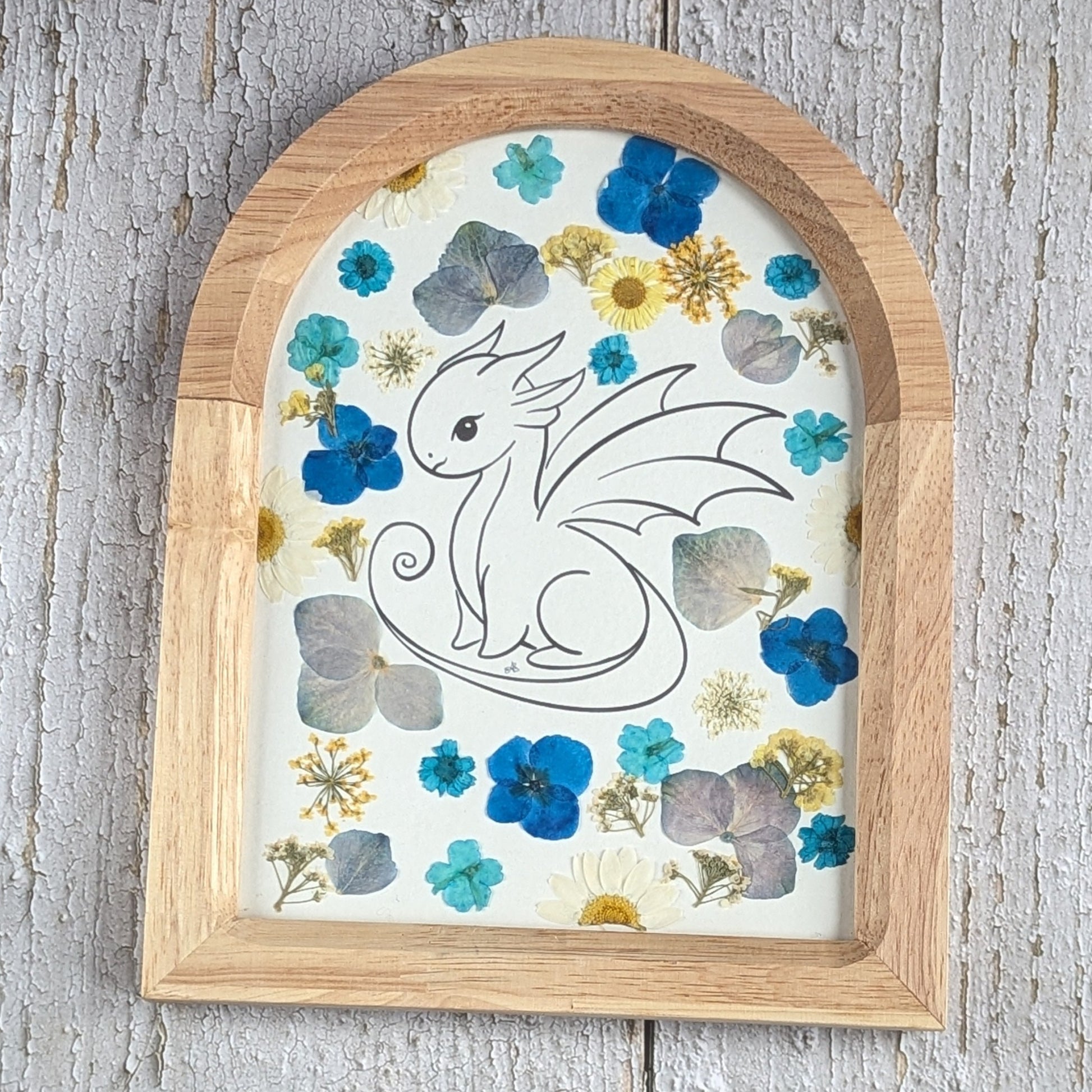 Cadre Faunéa en forme d’arche avec dessin imprimé d’un dragon entouré de fleurs séchées pressées bleues et naturelles