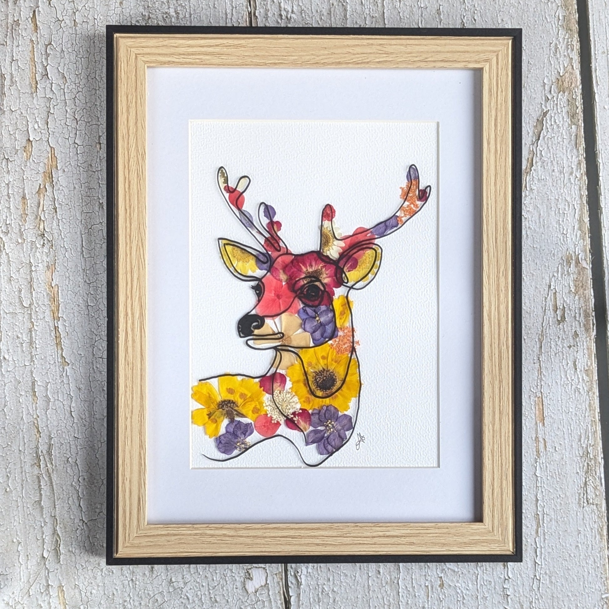 Cadre Faunéa avec dessin imprimé d’un cerf entouré de fleurs séchées pressées aux tons jaunes, rouges et violets