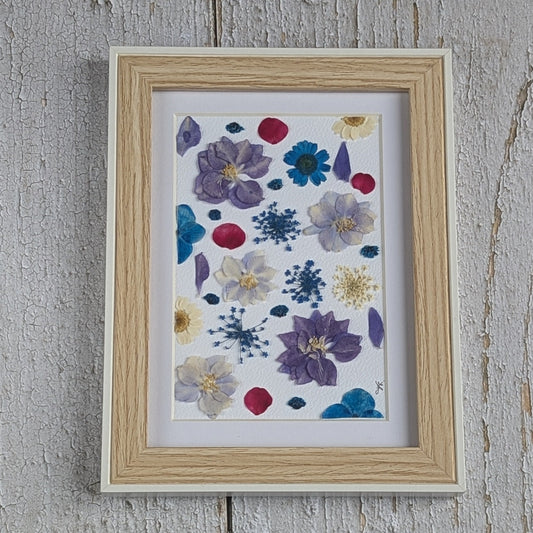 Détail du cadre en bois clair entourant une composition de fleurs séchées pressées Florésie