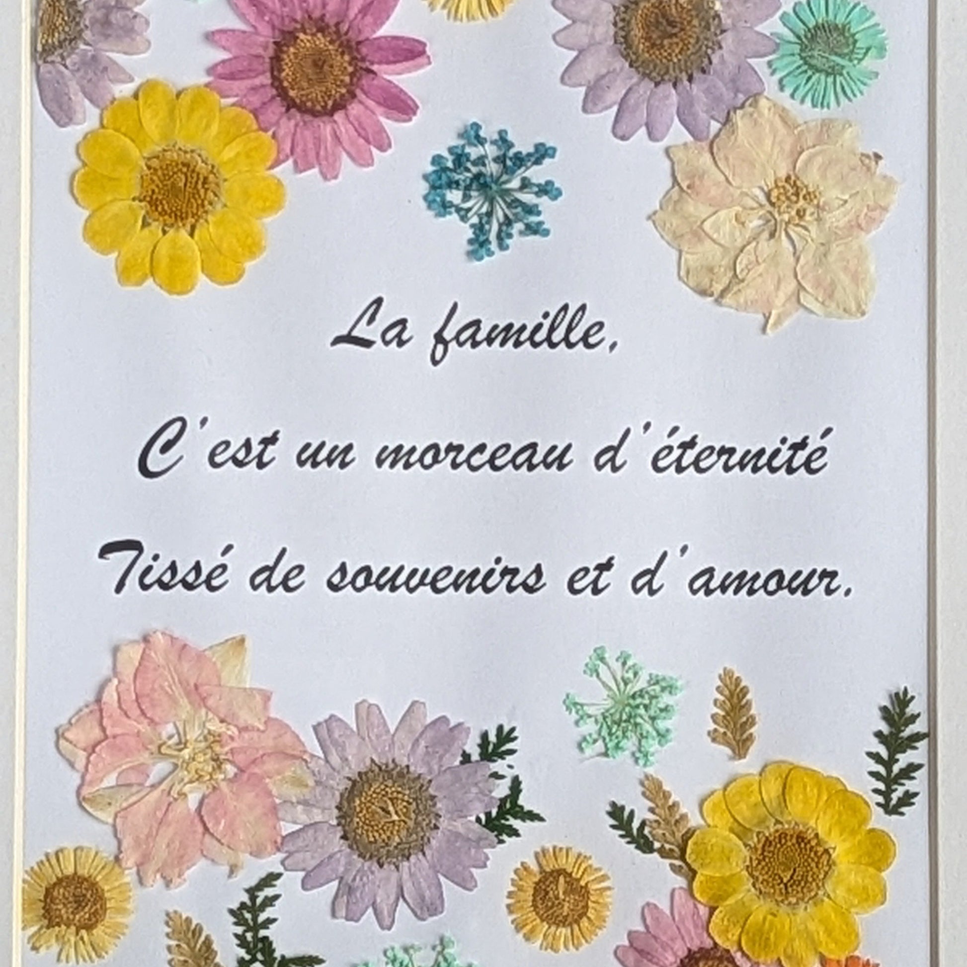Détail du texte inspirant sur la famille et des fleurs séchées pressées dans un cadre Florésie
