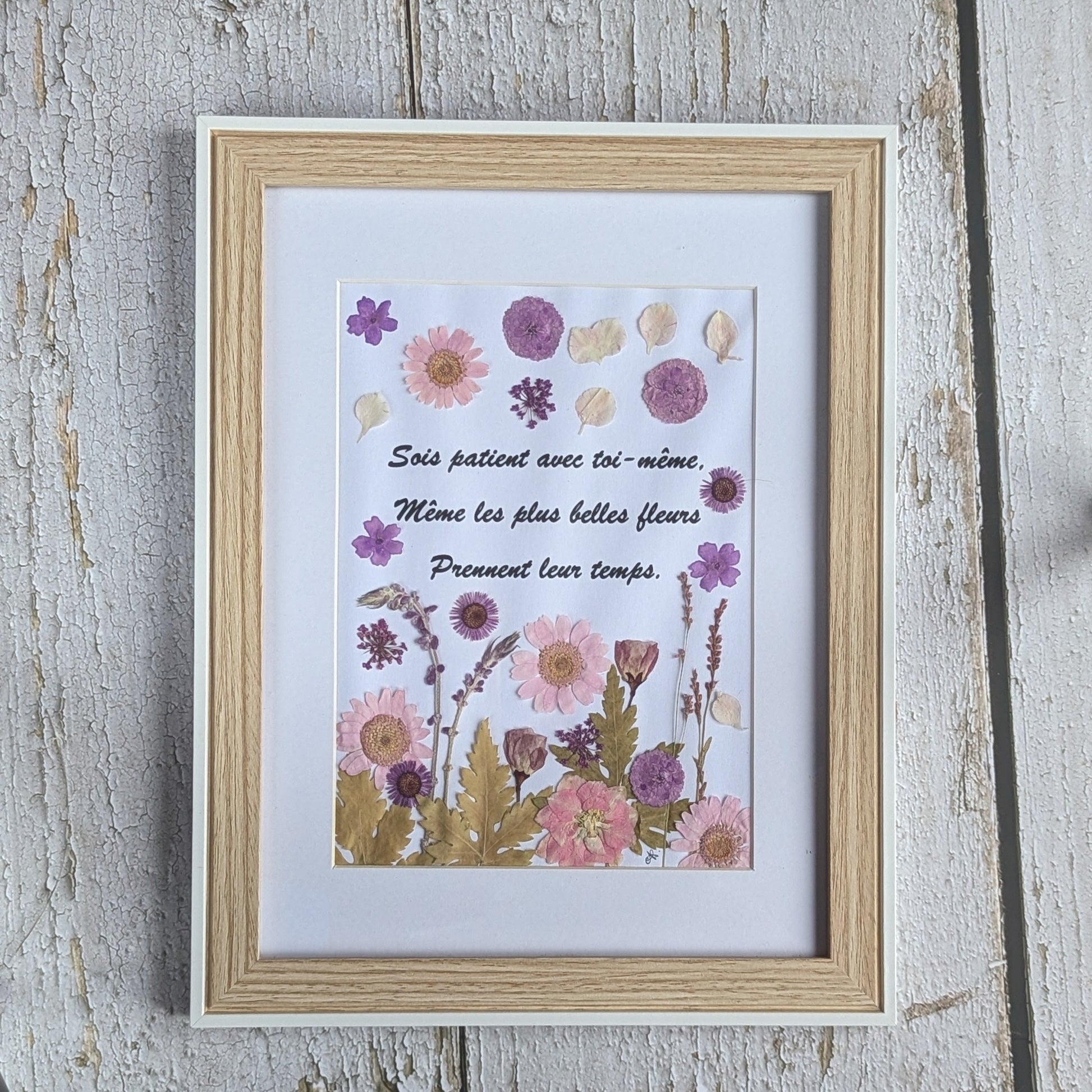 Cadre Florésie avec texte inspirant sur la patience entouré de fleurs séchées pressées aux tons roses et violets